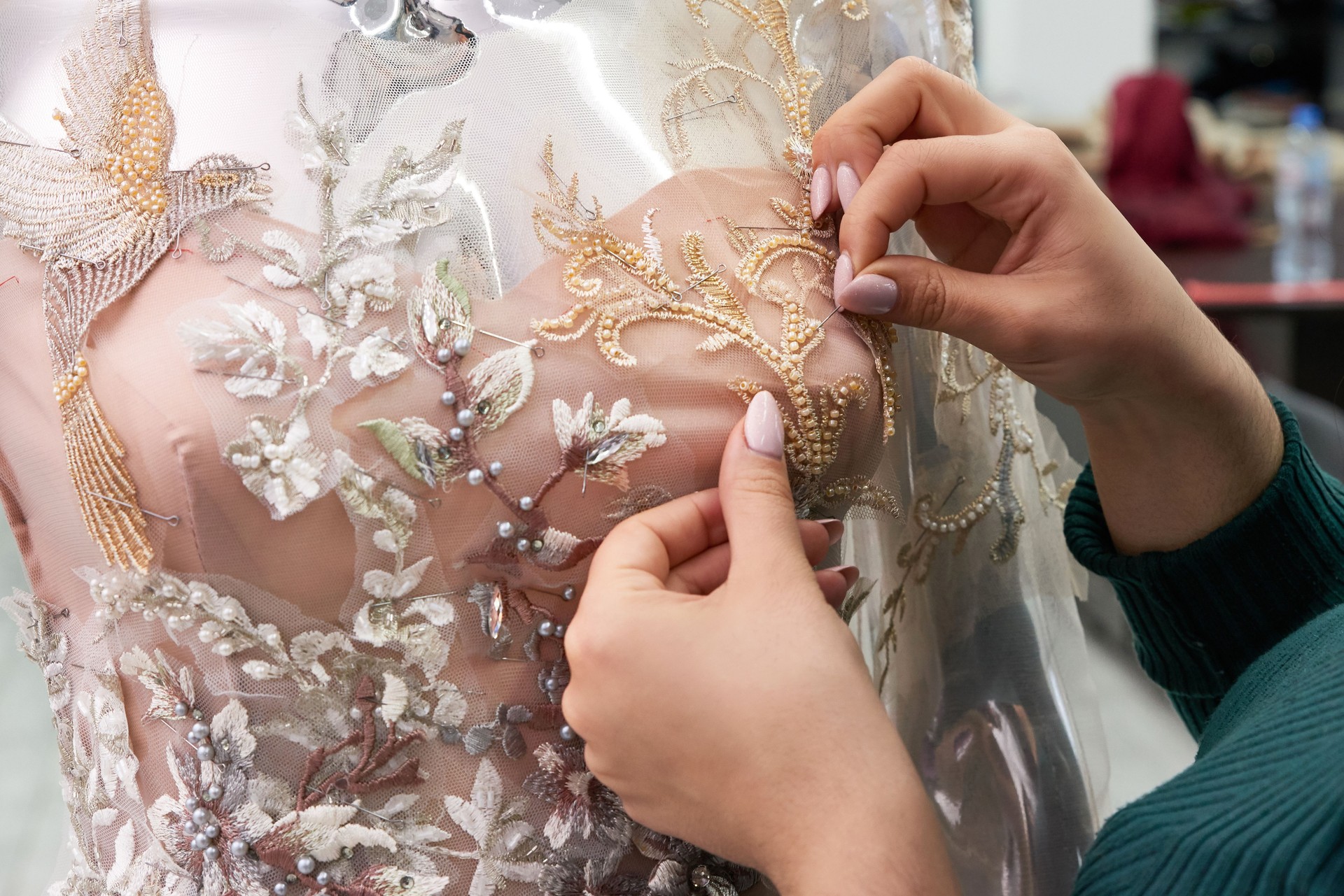 Dressmaker fixing white lace wedding dress on a mannequin in tailor studio